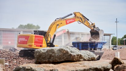 Bagger transportiert Schutt auf Baustelle