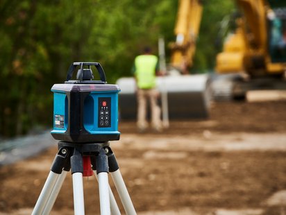 Präzisionsinstrument für Erdarbeiten mit Maschinerie im Hintergrund.