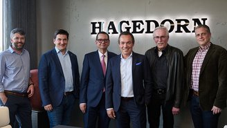 Führungsteam von Hagedorn vor Firmenlogo