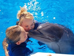 Kind küsst Delfin im klaren Wasser