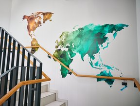 Treppenhaus mit farbenfroher Weltkarte an der Wand