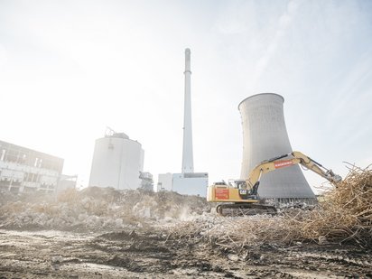 Effektiver Einsatz von Baumaschinen beim Felsabtrag nahe Kühlturm.