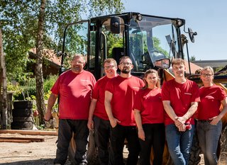 Unser Hagedorn-Team vereint vor Bagger, symbolisch für gegenseitige Hilfe.