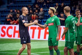 Spieler von zwei Teams bei Begrüßung auf dem Feld