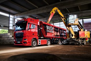 Großer roter LKW wird mit Baumaschinen beladen