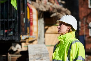 Bauarbeiterin beobachtet Maschinenarbeit auf Baustelle